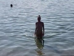 Naked Monika Fox swims in the sea and walks along the beach on a public beach