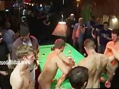 Sexy hunk laying on pool table among horde of gay cocks is fucked