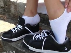 Beautiful girl takes socks and sneakers off in a park