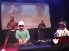 Two men pull a girl's panties down on a stage, exposing her pussy