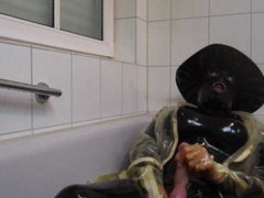 Latex Isa with rubber mask and big hat in the bathtub